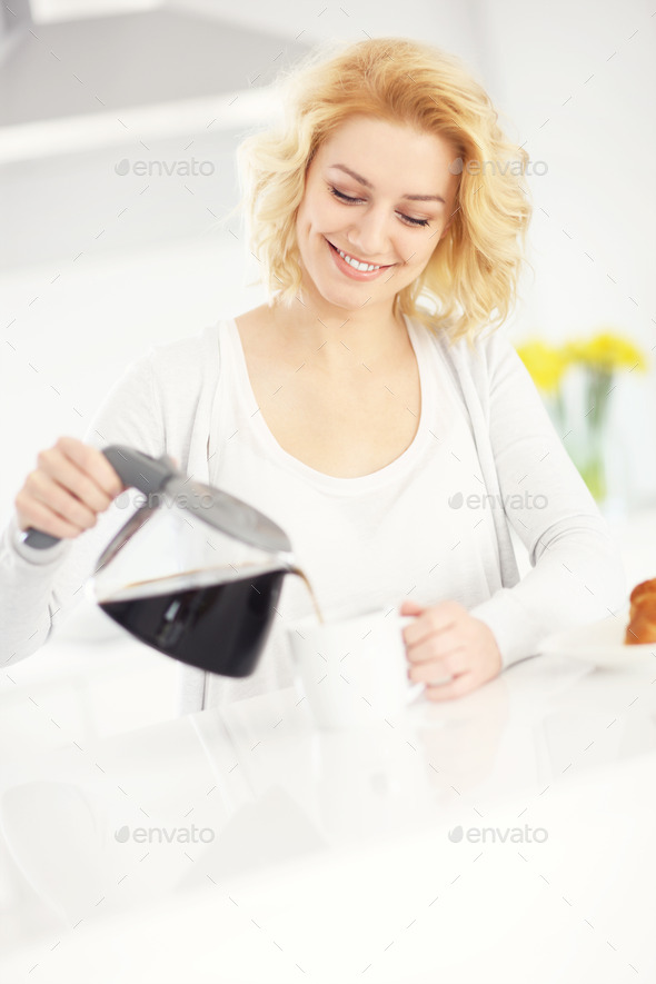 Woman pouring coffee in the kitchen