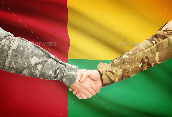 Men in uniform shaking hands with flag on background - Guinea-Bissau
