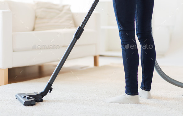 close up of woman legs with vacuum cleaner at home