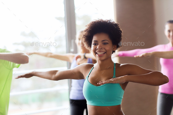 group of smiling people dancing in gym or studio