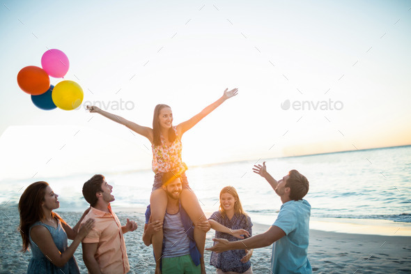 Happy friends dancing on the sand with balloon at the beach