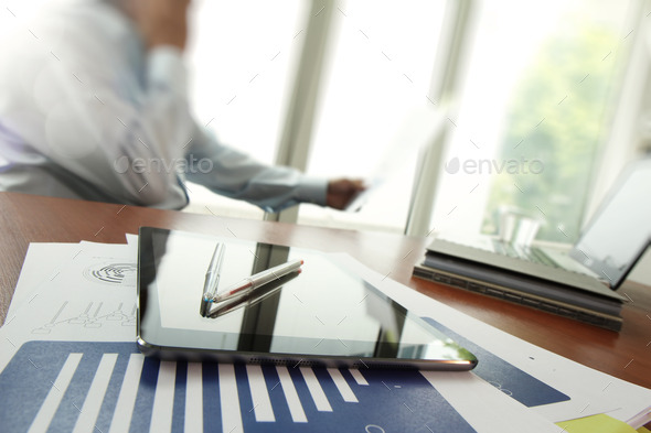 business documents on office table with digital tablet and man w