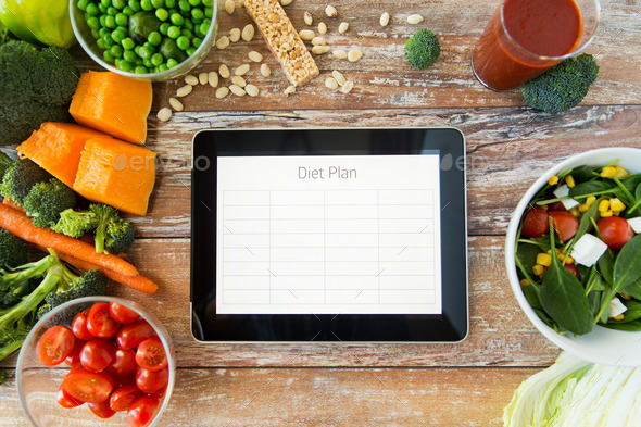 close up of diet plan on tablet pc and vegetables
