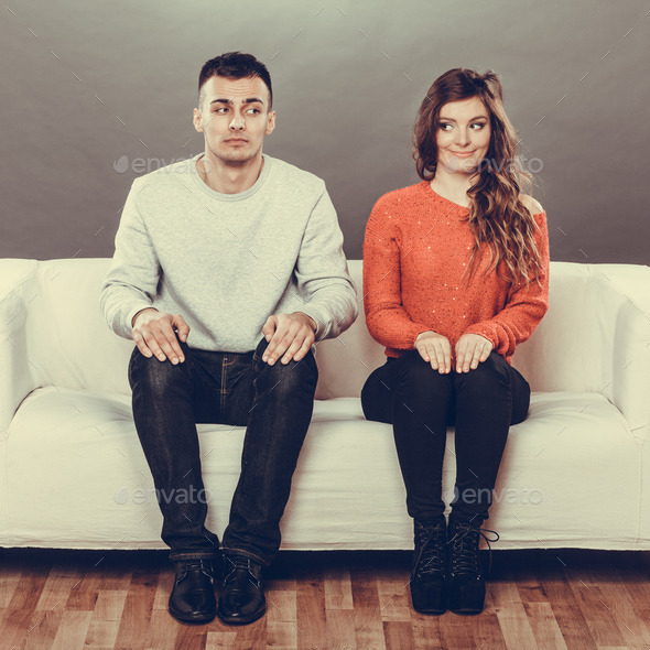 Shy woman and man sitting on sofa. First date.