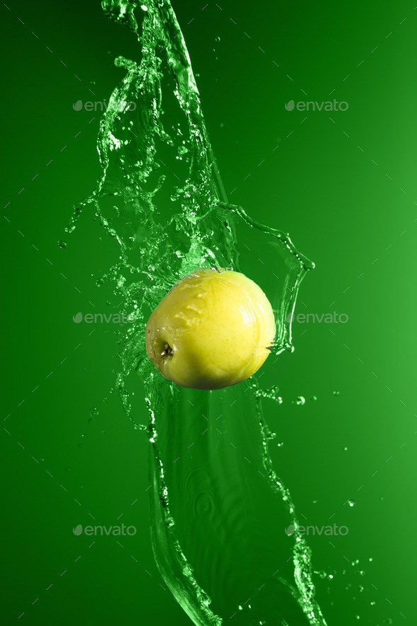 Green apple with water splash, on green