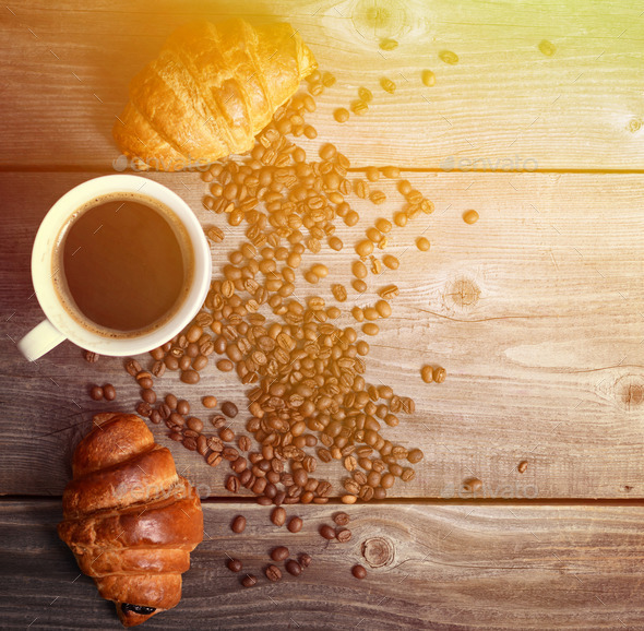 Coffee and fresh croissant on wooden background