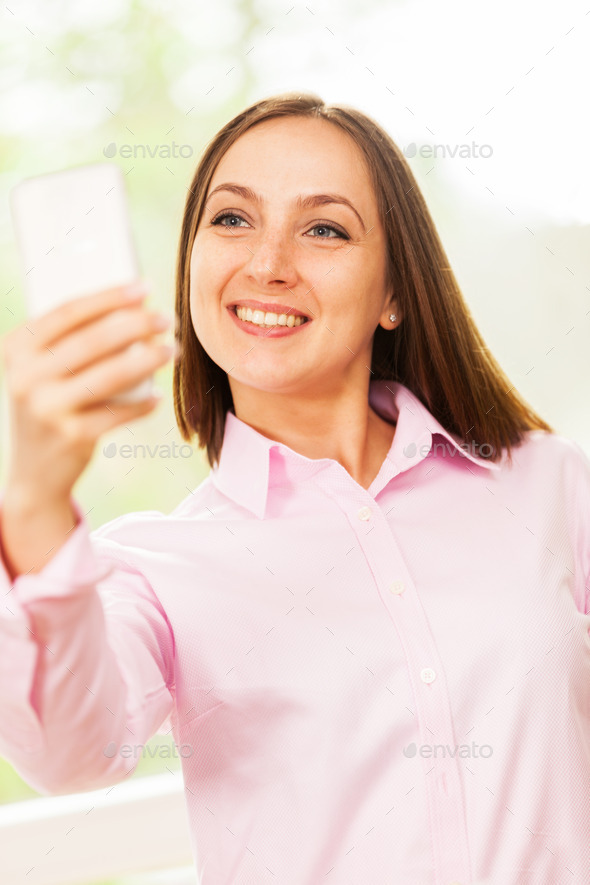 Smiling caucasian woman with pink shirt is doing a selfie with h (Misc) Photo Download