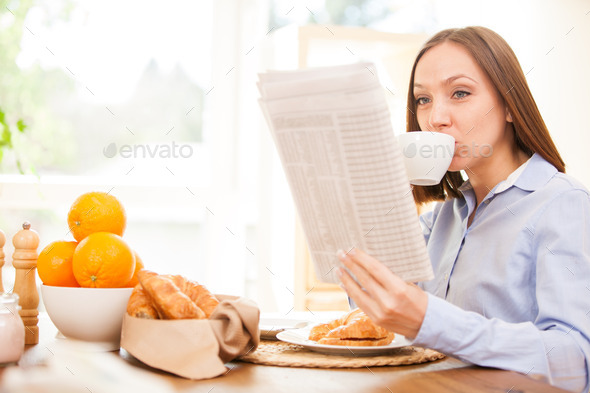 Businesswoman is reading the newspaper while having breakfast (Misc) Photo Download