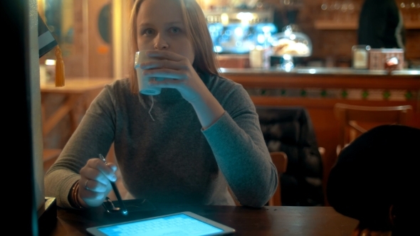 Woman Using Tablet PC With Stylus In Cafe Woman Using Tablet PC With Stylus In Cafe