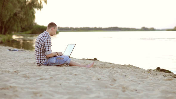 Man Resting a Laptop on the Beach Man Resting a Laptop on the Beach