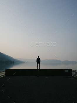 Man standing on a pier wall looking at a swiss lake view