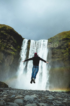 man jumping in front of waterfall