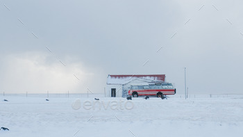 Picture of a red bus with a snowstorm just breaking