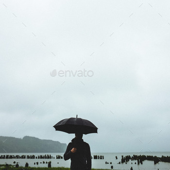 Man standing in the rain near ancient pier