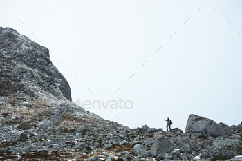Man hiking to mountaintop in the fog.