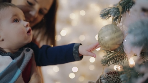 Mother Decorating Christmas Tree With Her Baby