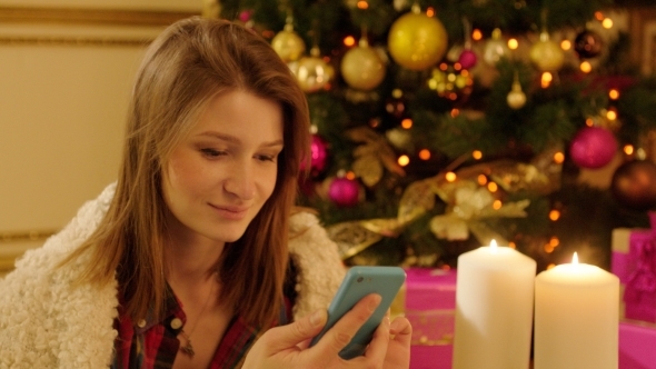 Woman With Smartphone By Christmas Tree