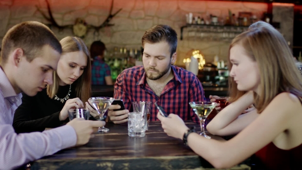 millennials staring at phones at restaurant