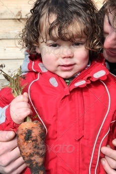 Little boy holding organic carrot