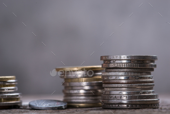 Photodune Stack of assorted coins on the wooden table over the grey concrete wall 18769340