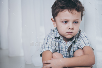 Photodune Portrait of sad little boy sitting near the window 18788072