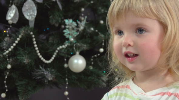 Little Girl Handed a Christmas Present Near Christmas Tree