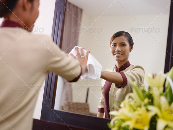 Asian maid working in hotel room and smiling