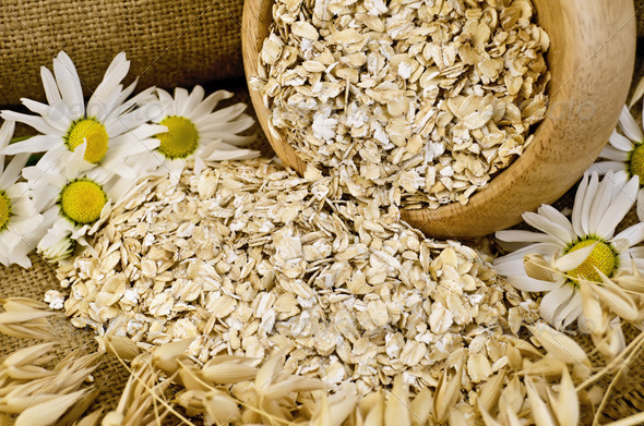 Oat flakes in a wooden bowl with chamomiles