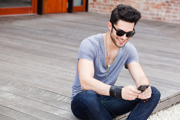 attractive young male model texting on a smartphone