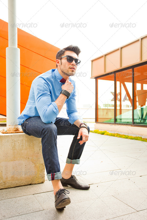 handsome young male model posing outdoors in blue shirt and sunglasses