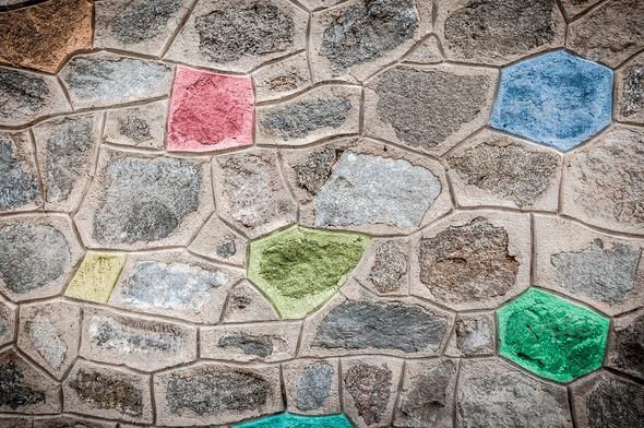 Grey stone wall with bright colored blocks.