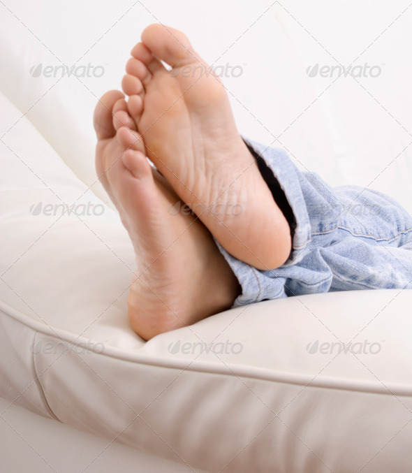 Barefoot young woman on sofa, focus on foot soles
