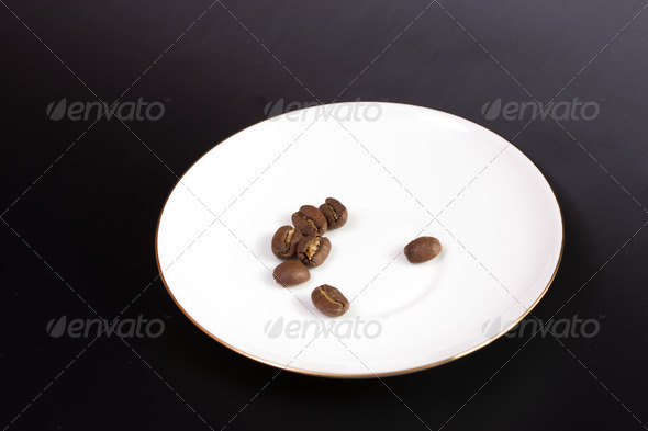 coffee grain on a round white plate on a black backgroundcoffee