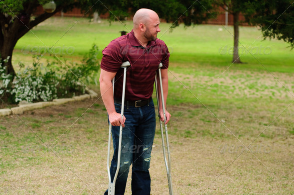Muscular bald man on crutches