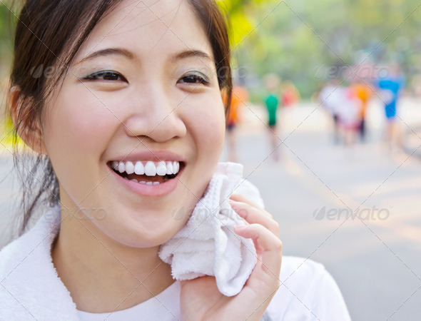 Asian woman wiping sweat with a towel after exercising