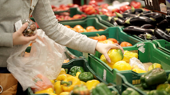 Woman In A Supermarket Choosing Vegetables Woman In A Supermarket Choosing Vegetables