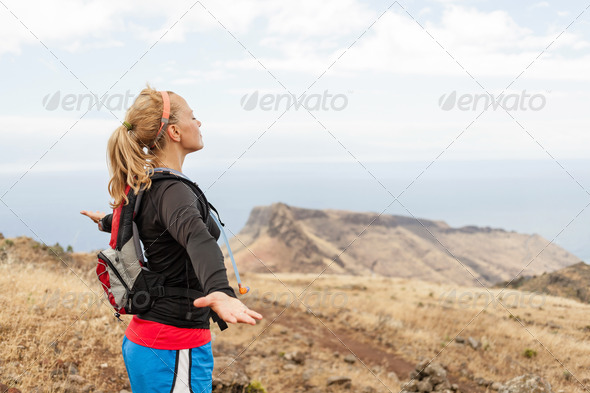 Woman runner, arms outstreched in mountains