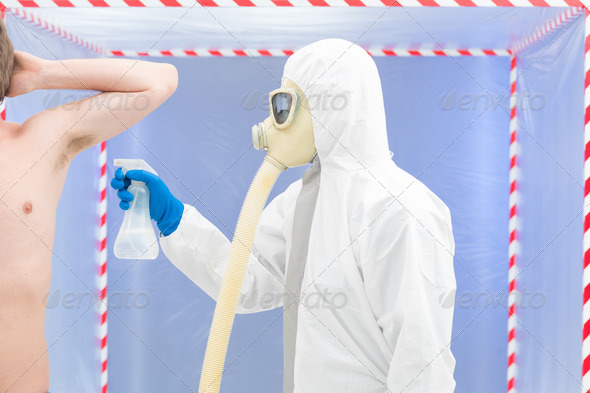 biohazard geared person disinfecting a man - Stock Photo - Images