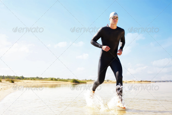 Triathlete running in to the water - Stock Photo - Images