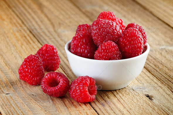 Raspberries in bowl on wooden background