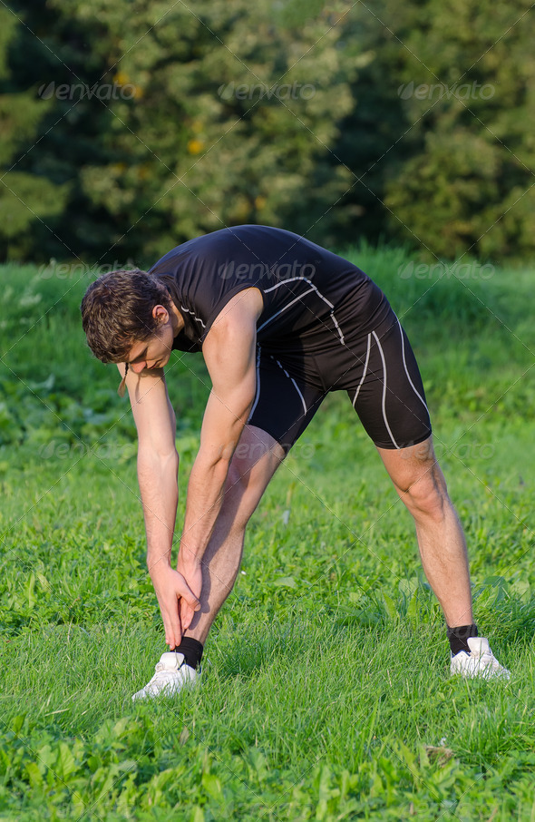 Young sportsman stretching before workout in park - Stock Photo - Images