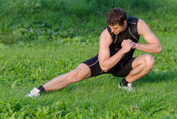 Young sportsman warming up before workout in park - Stock Photo - Images