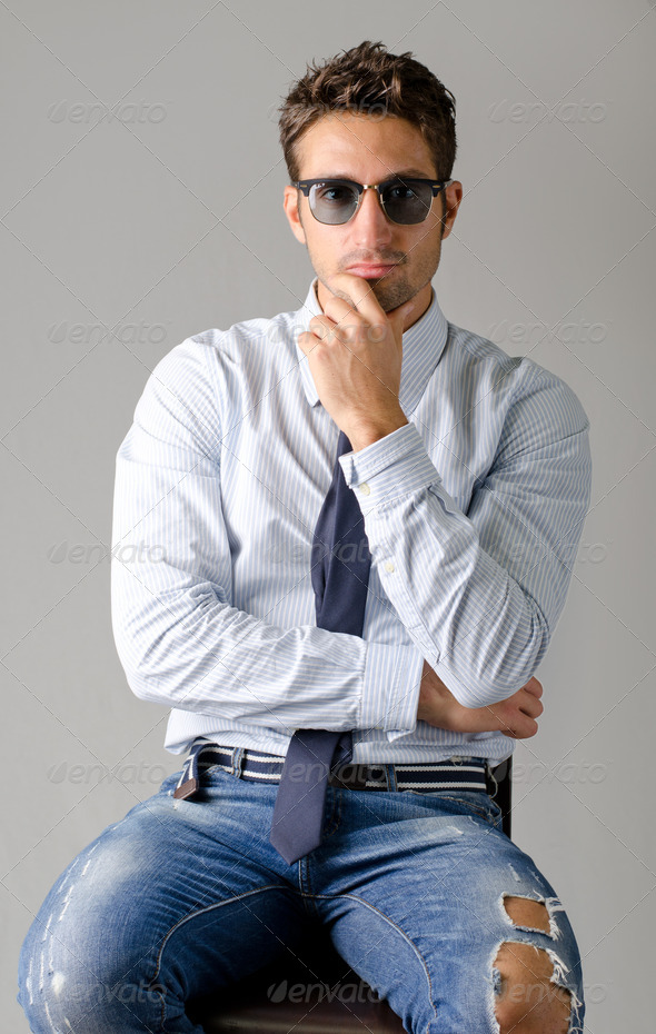 Handsome young man wearing shirt, necktie and ripped jeans