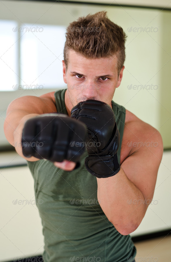 Young man with boxer27;s gloves throwing punch towards camera