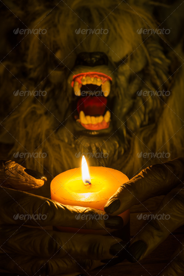 Werewolf head and the hands cradling a burning candle