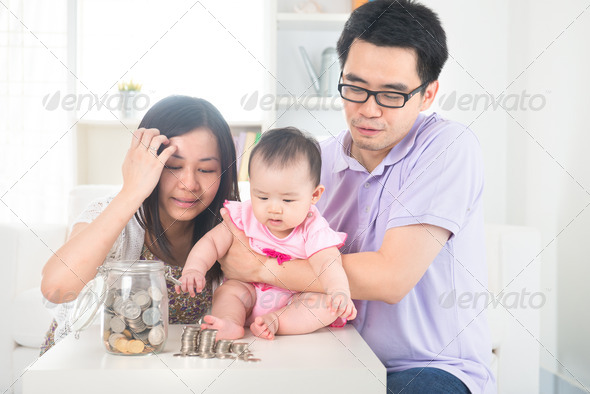 Asian baby putting coins into the glass bottle with help of pare