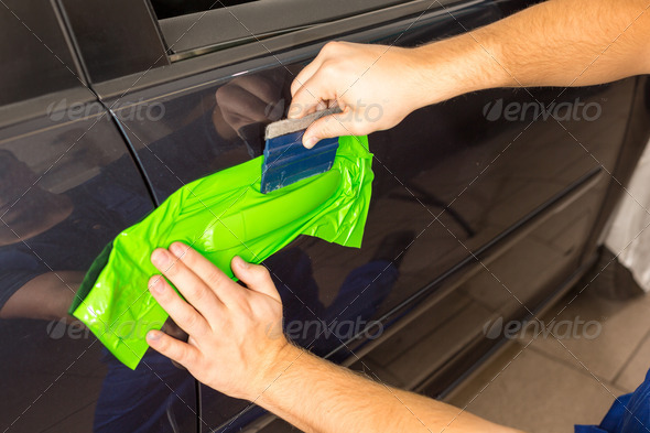 Car wrapping specialist wraps a car door handle with adhesive foil or film