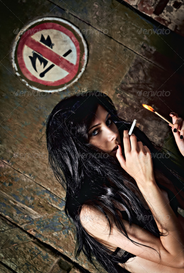 Beautiful young girl lights a cigarette near \