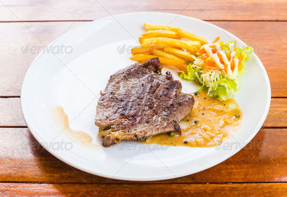 beef steak on white dish with salad and french fries