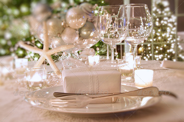 Elegantly lit holiday dinner table with white ribbon gift